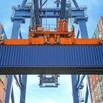 Shore crane loading containers in freight ship